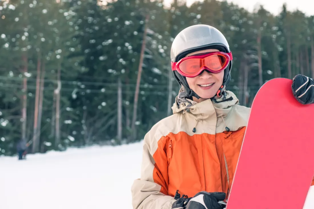 Mloda snowboardzistka w kasku i goglach na stoku narciarskim